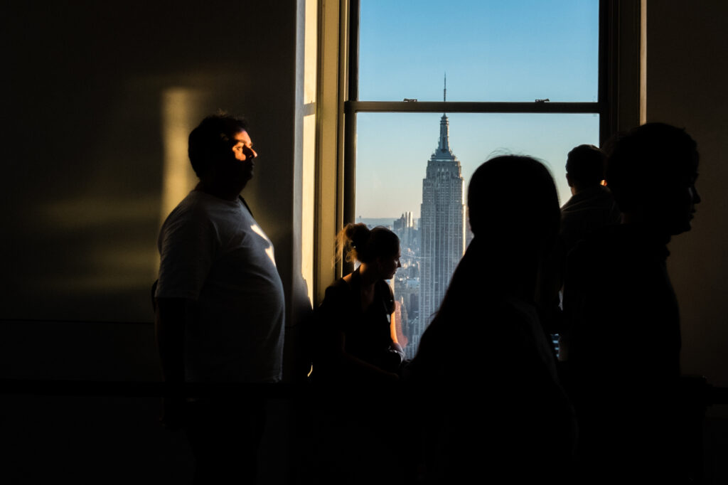 Tourists in silhouette viewing the Empire State Building from Top of the Rock at sunset in New York City